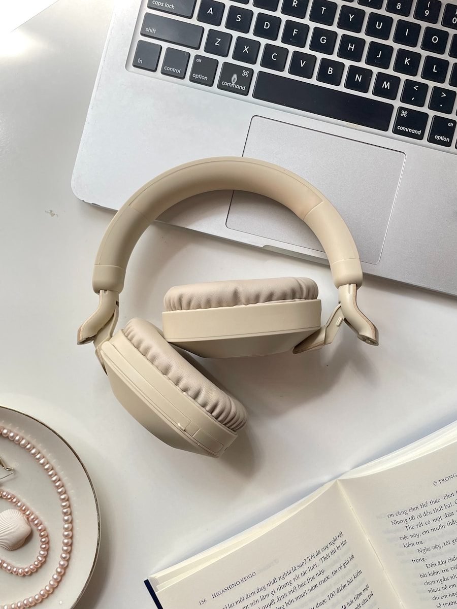 Beige headphones rest on a laptop with an open book.