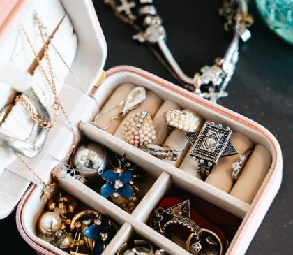 A pink jewelry box filled with necklaces and rings.